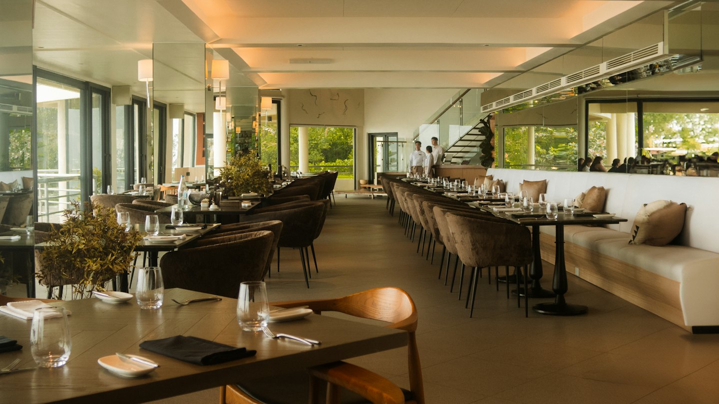 Modern restaurant dining room set for service with staff nearby.