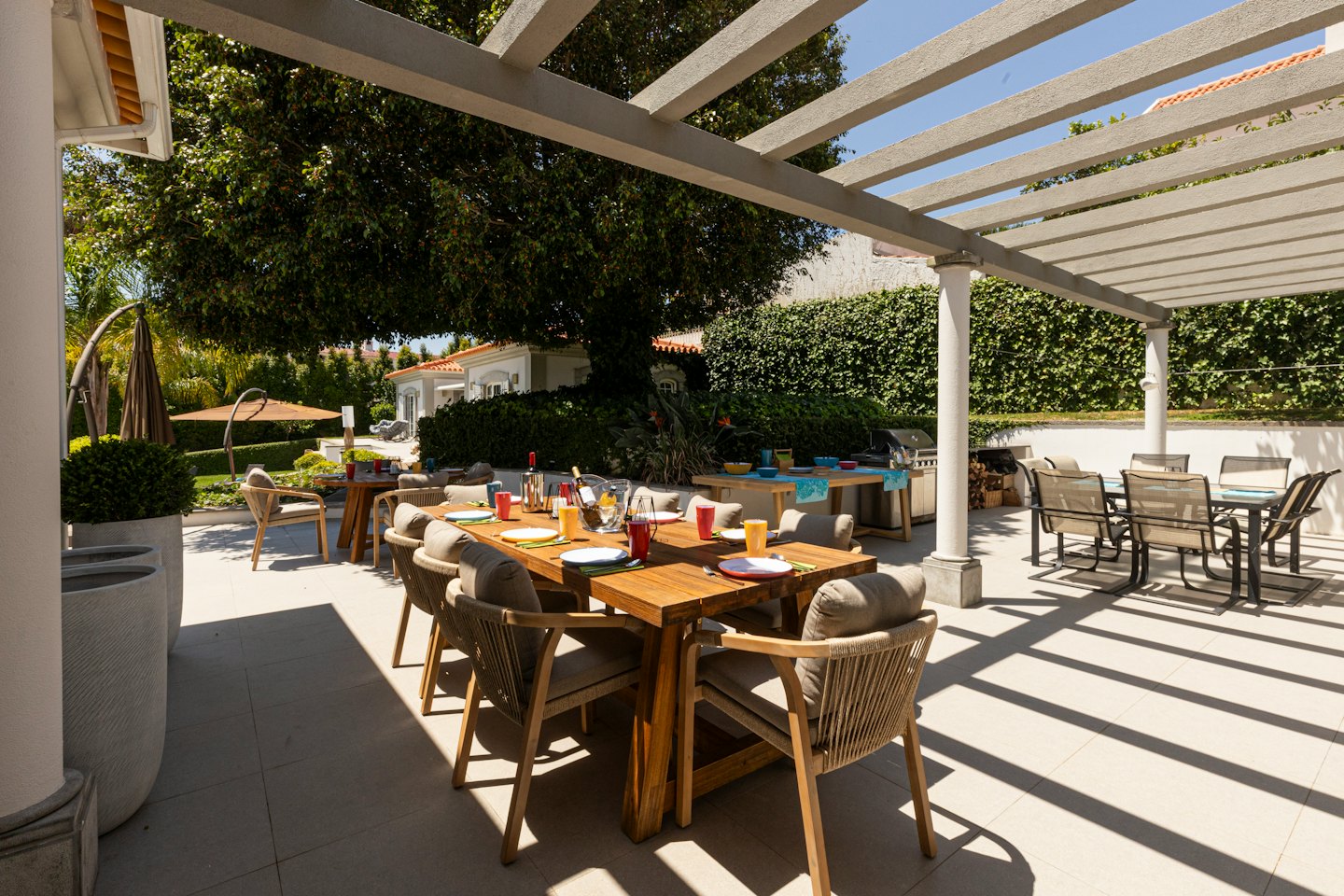 Wooden table set for a meal on a sunny outdoor patio.