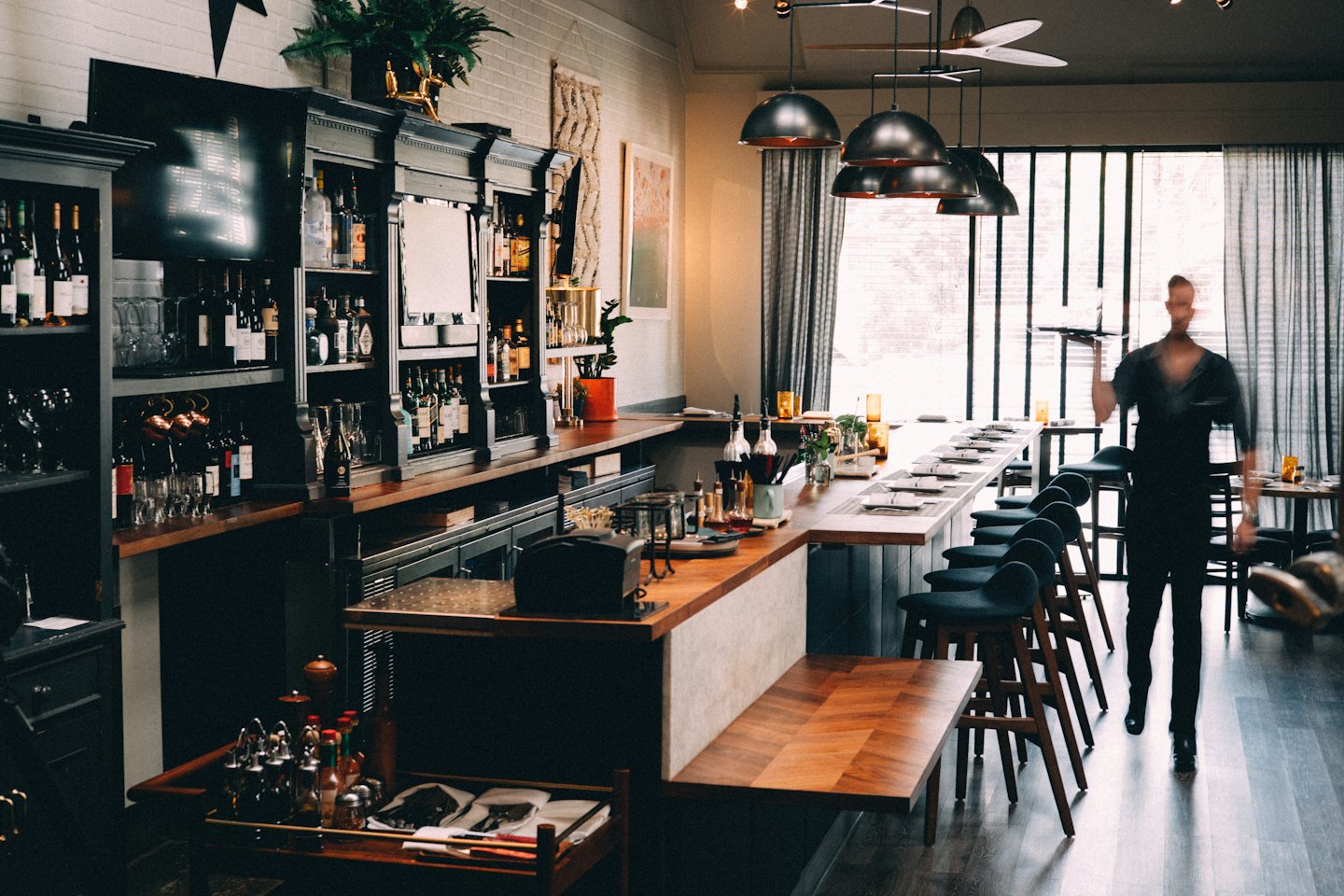 Modern bar with wooden counter and stocked backbar.